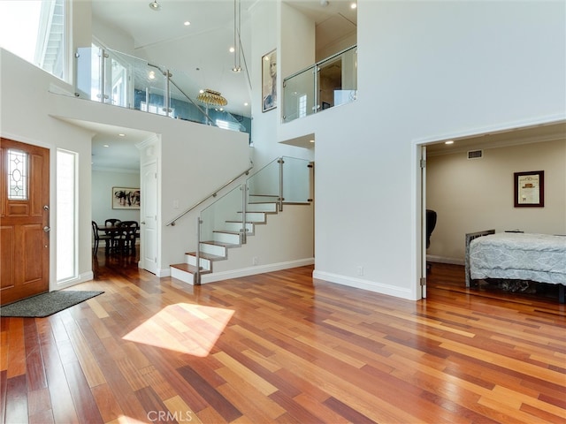 foyer entrance with light wood-type flooring and a towering ceiling