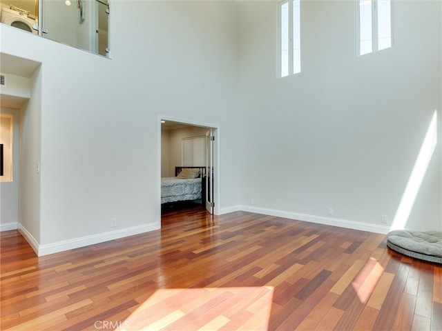 unfurnished living room with wood-type flooring and a high ceiling