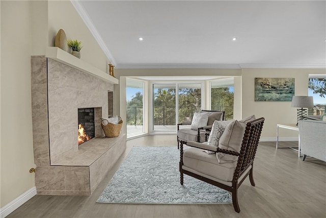 living room with a tiled fireplace, crown molding, light hardwood / wood-style floors, and lofted ceiling