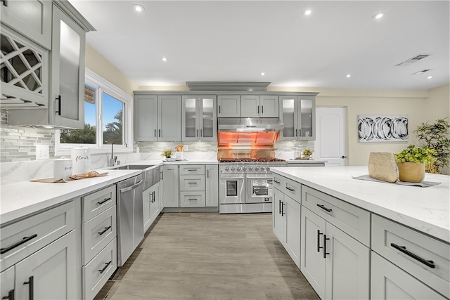 kitchen with decorative backsplash, light stone countertops, and appliances with stainless steel finishes