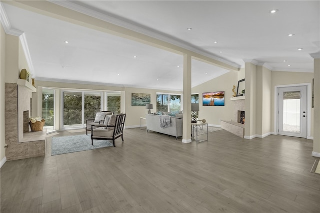 living room with hardwood / wood-style floors, a fireplace, lofted ceiling with beams, and ornamental molding