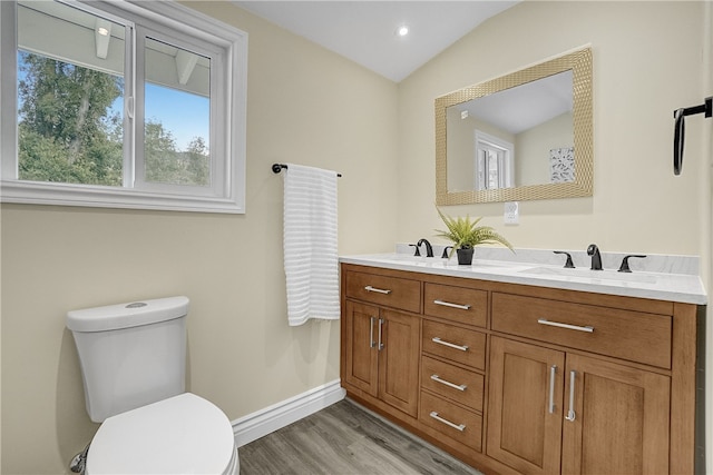 bathroom with hardwood / wood-style floors, vanity, toilet, and vaulted ceiling