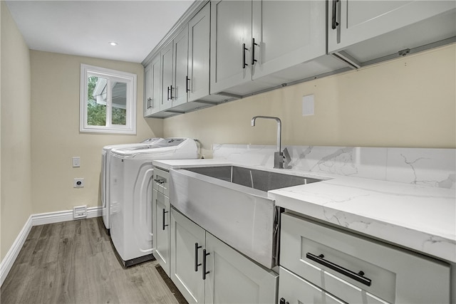 washroom featuring washer and dryer, cabinets, light wood-type flooring, and sink