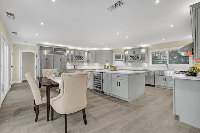 kitchen with wine cooler, stainless steel appliances, a kitchen island, and wall chimney exhaust hood