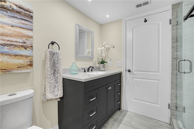 bathroom featuring vanity, toilet, and a shower with door