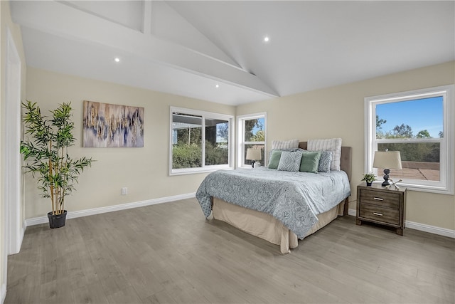 bedroom featuring light hardwood / wood-style floors, multiple windows, and lofted ceiling