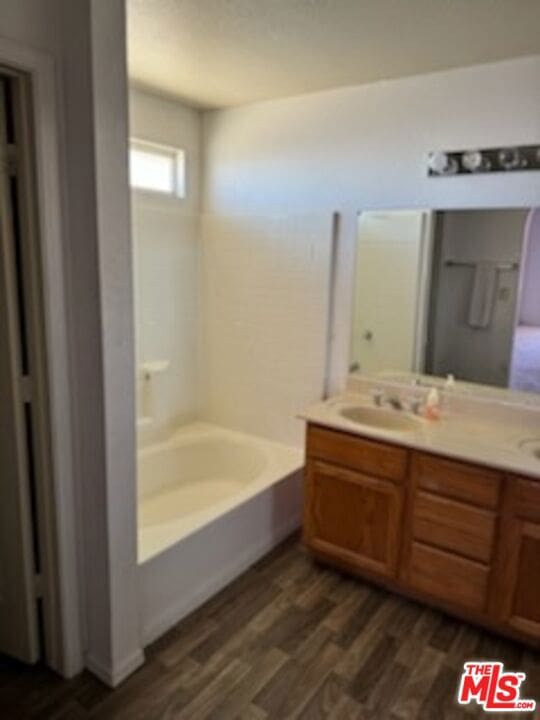 bathroom with vanity, a tub to relax in, and hardwood / wood-style floors