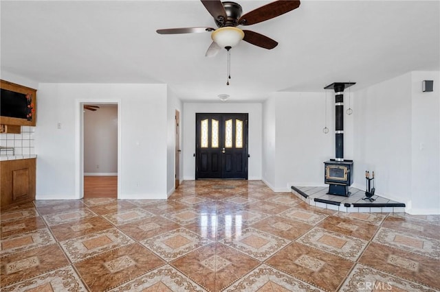 entrance foyer with ceiling fan and a wood stove