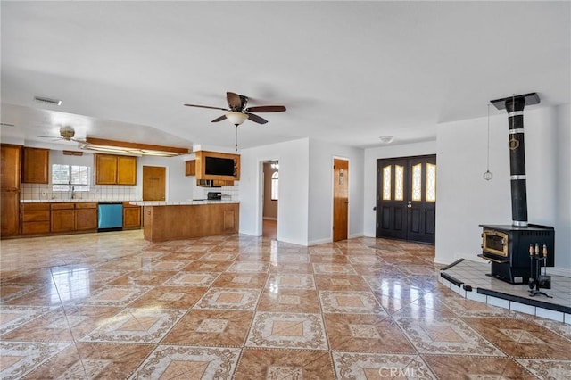 kitchen with backsplash, a wood stove, ceiling fan, and dishwasher