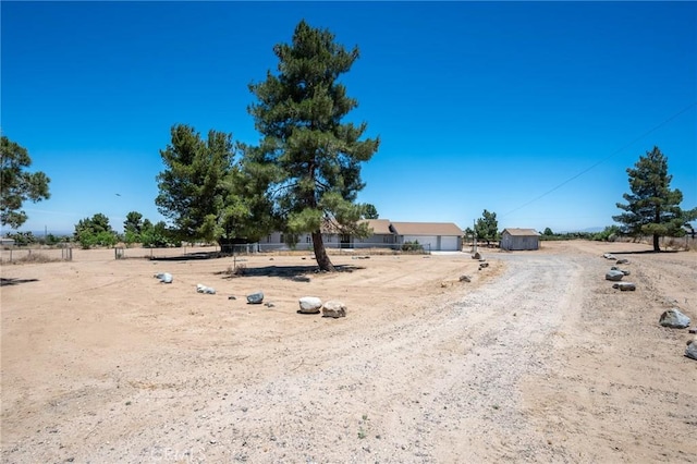 view of yard featuring a garage, a rural view, and fence