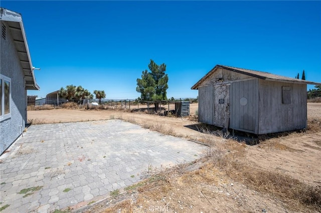 view of yard featuring a shed, fence, a patio, and an outdoor structure