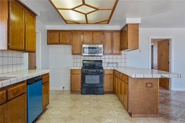 kitchen featuring brown cabinetry, tile countertops, dishwashing machine, stainless steel microwave, and gas stove