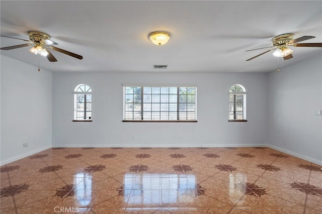 unfurnished room with a ceiling fan, visible vents, and baseboards