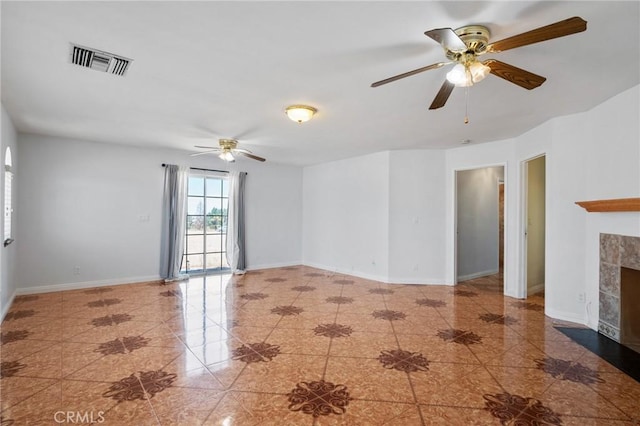 empty room featuring ceiling fan and a tiled fireplace