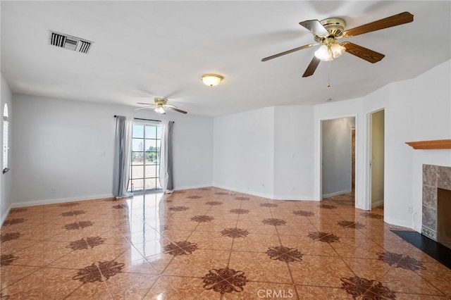 unfurnished room with ceiling fan, a fireplace, visible vents, and baseboards