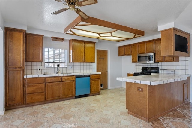 kitchen featuring decorative backsplash, kitchen peninsula, stainless steel appliances, sink, and tile countertops