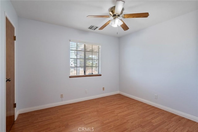 spare room featuring light wood finished floors, ceiling fan, and baseboards