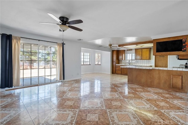 interior space featuring backsplash, ceiling fan, and tile counters