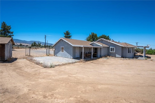 view of front of property featuring a mountain view and a storage shed