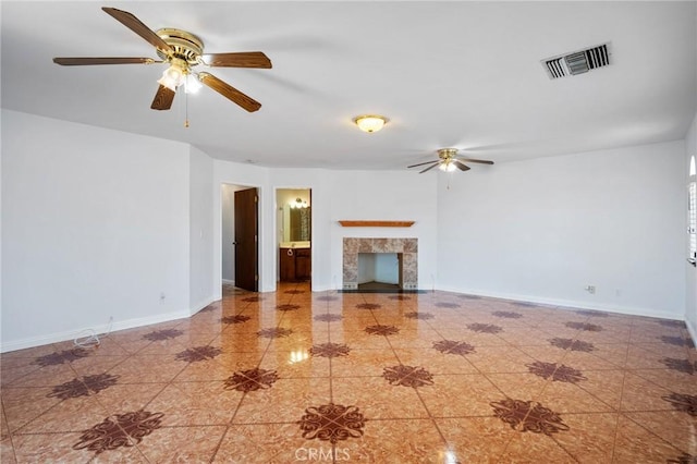 unfurnished living room featuring a ceiling fan, baseboards, visible vents, and a tiled fireplace