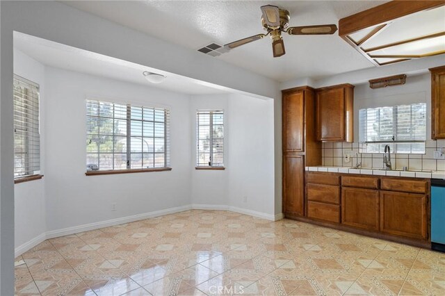 kitchen featuring ceiling fan, sink, tile counters, decorative backsplash, and light tile patterned floors