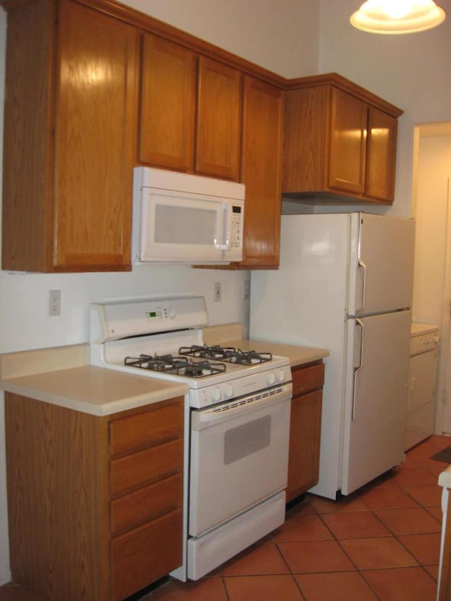 kitchen featuring tile patterned flooring, white appliances, and washer / dryer