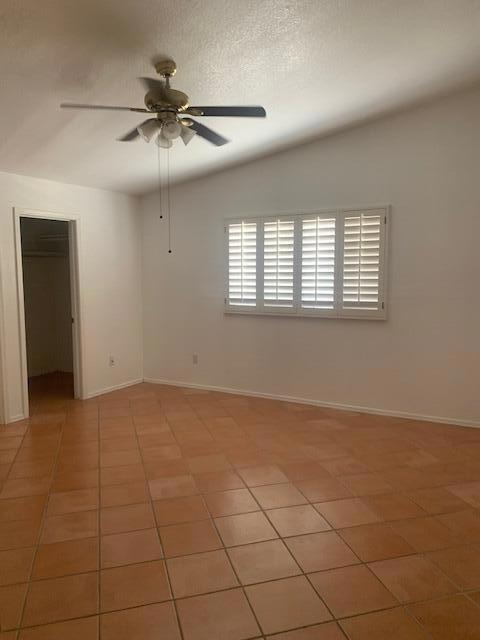 tiled spare room with ceiling fan and a textured ceiling