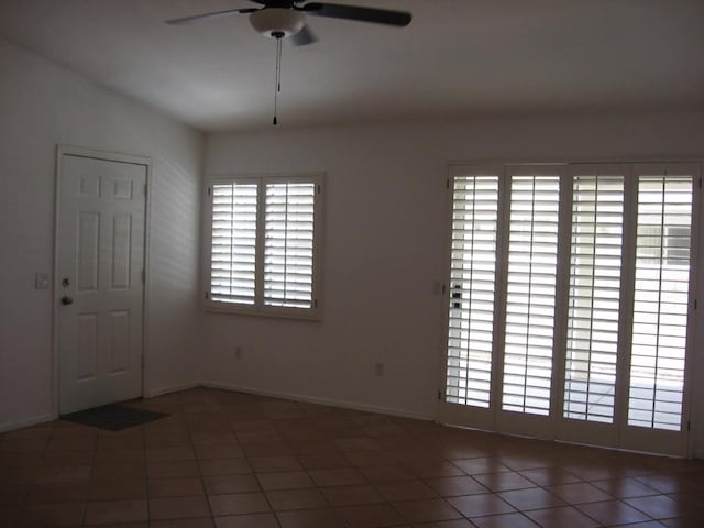 tiled spare room featuring ceiling fan