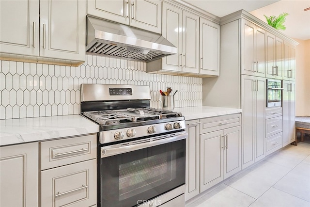 kitchen featuring decorative backsplash, light tile patterned floors, light stone counters, and stainless steel range with gas stovetop