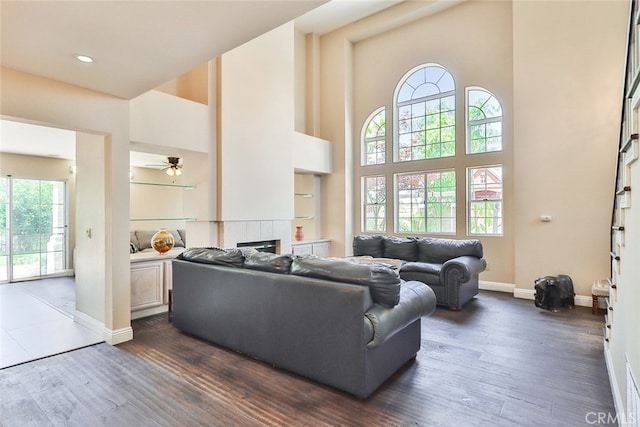 living room featuring dark hardwood / wood-style floors, a tiled fireplace, and plenty of natural light