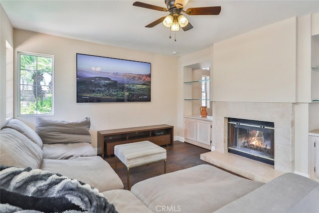 living room featuring dark wood-type flooring, a tiled fireplace, and ceiling fan