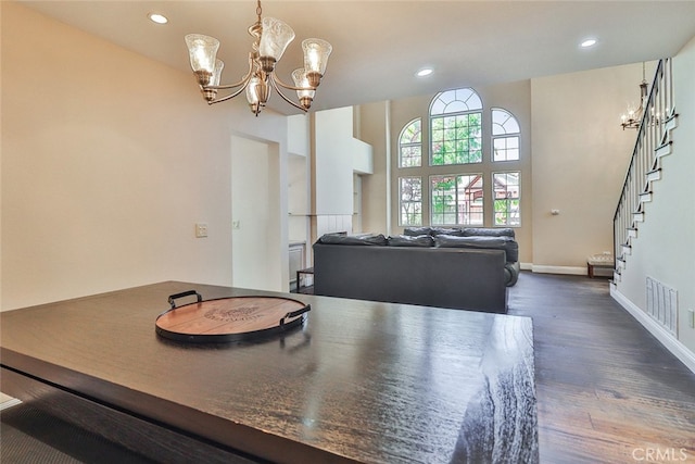 dining area featuring a chandelier, dark hardwood / wood-style floors, and a towering ceiling