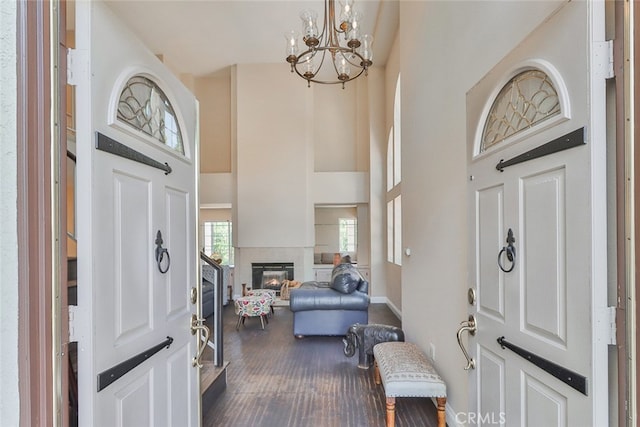 foyer entrance with a towering ceiling, wood-type flooring, and an inviting chandelier