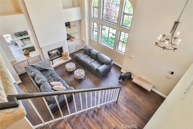 living room featuring an inviting chandelier, a high ceiling, dark wood-type flooring, and built in features