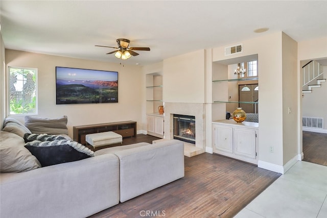 living room featuring built in features, dark wood-type flooring, and ceiling fan