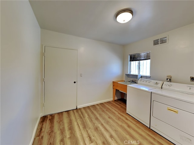 clothes washing area with separate washer and dryer and light hardwood / wood-style flooring