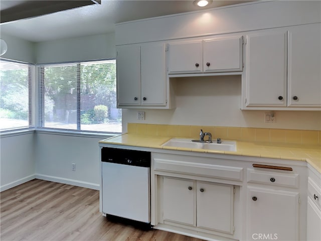 kitchen with white cabinets, dishwasher, sink, tile countertops, and light hardwood / wood-style flooring