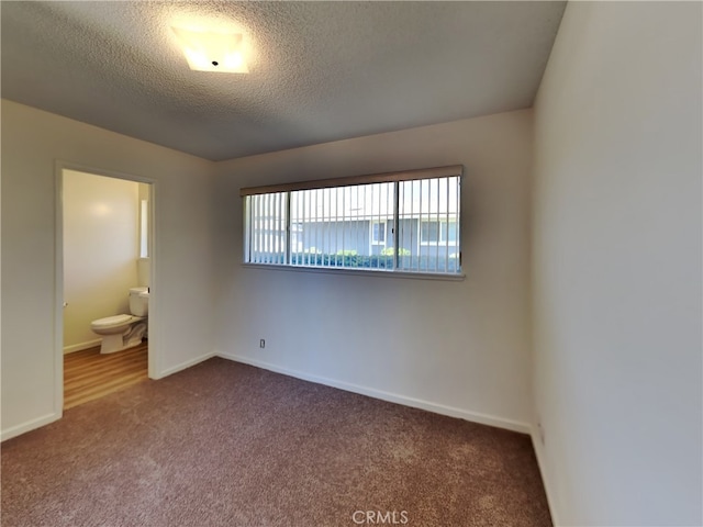 unfurnished bedroom with carpet floors, connected bathroom, and a textured ceiling