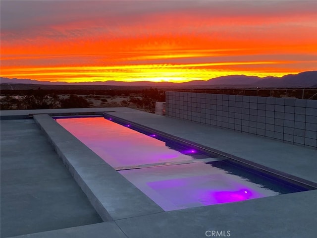 pool at dusk featuring a mountain view