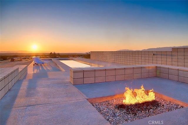 pool at dusk with a fire pit