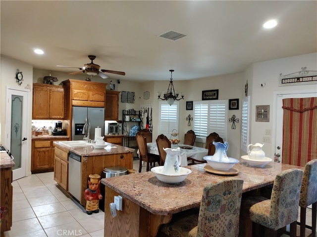 kitchen with sink, a kitchen island, decorative light fixtures, stainless steel appliances, and ceiling fan with notable chandelier