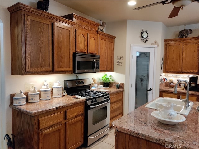 kitchen featuring light stone countertops, ceiling fan, appliances with stainless steel finishes, and sink