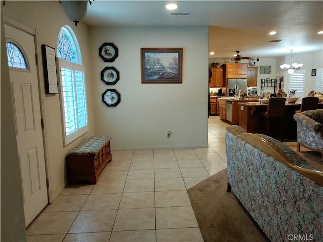 entryway with ceiling fan with notable chandelier, light tile patterned flooring, and a wealth of natural light