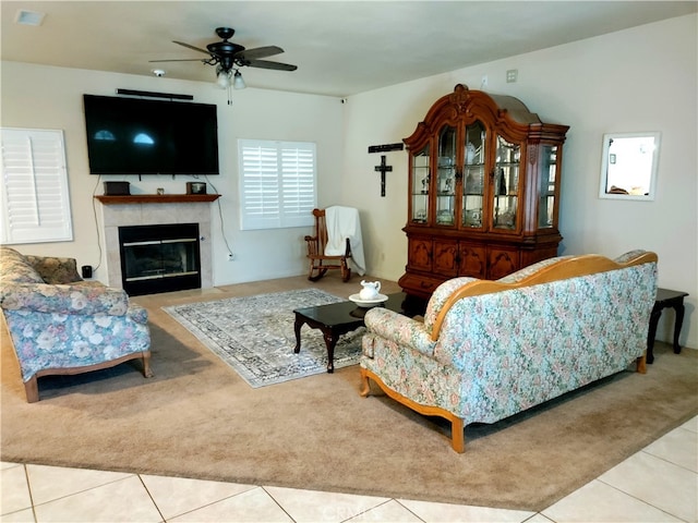 living room featuring ceiling fan, a fireplace, and light tile patterned floors