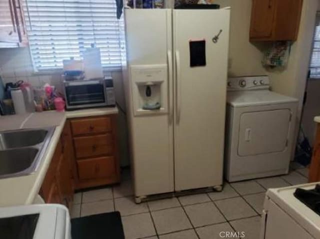 kitchen featuring sink, white fridge with ice dispenser, light tile patterned floors, and washer / clothes dryer