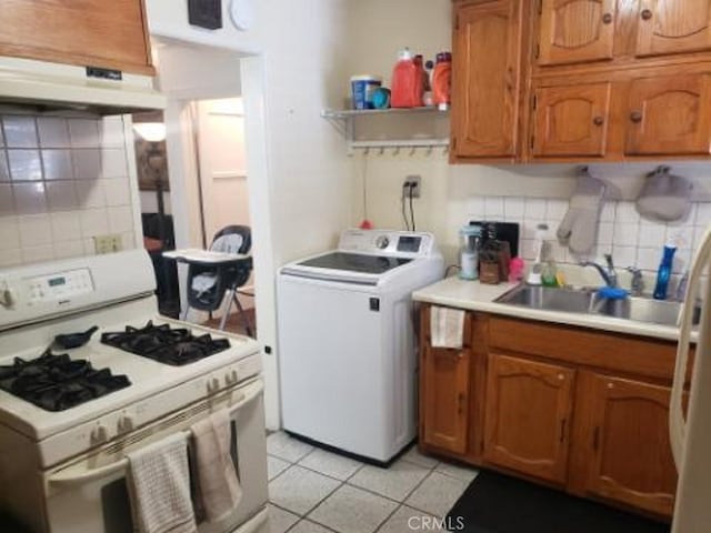 kitchen featuring white gas stove, washer / clothes dryer, sink, decorative backsplash, and light tile patterned floors