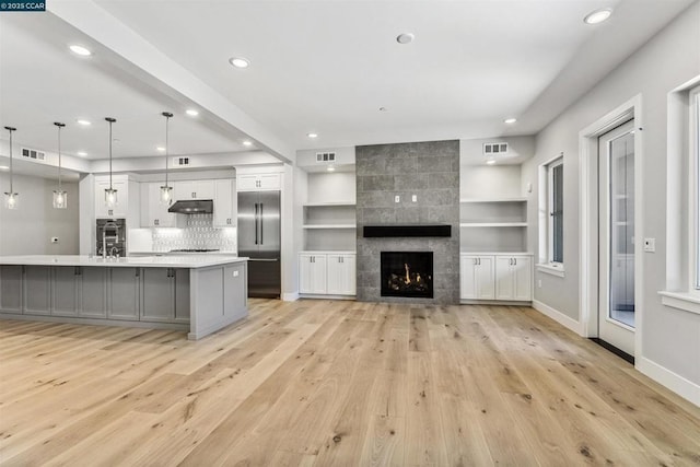 kitchen with a large island, gray cabinets, decorative light fixtures, a fireplace, and built in fridge