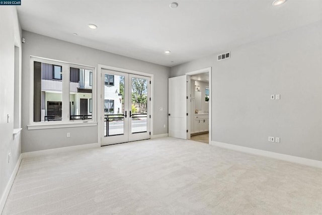 spare room featuring light colored carpet and french doors