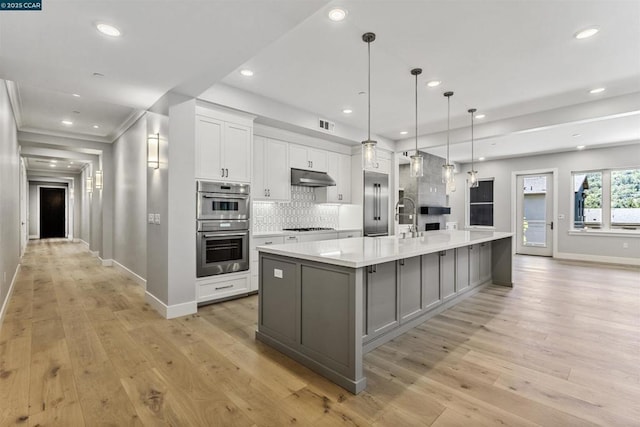 kitchen with hanging light fixtures, white cabinets, a spacious island, and stainless steel double oven