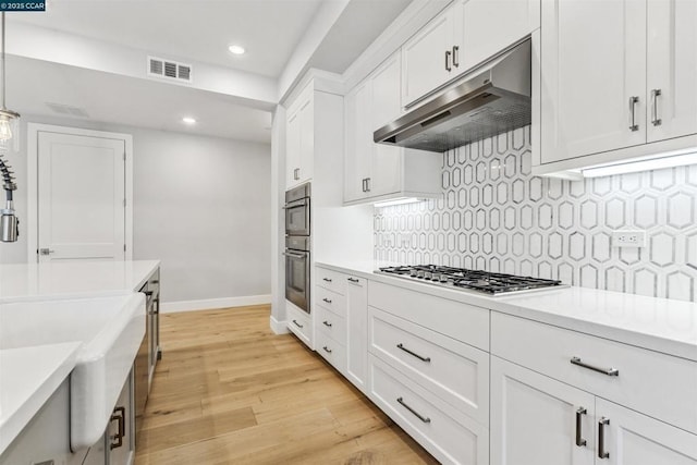 kitchen featuring white cabinets, appliances with stainless steel finishes, and pendant lighting